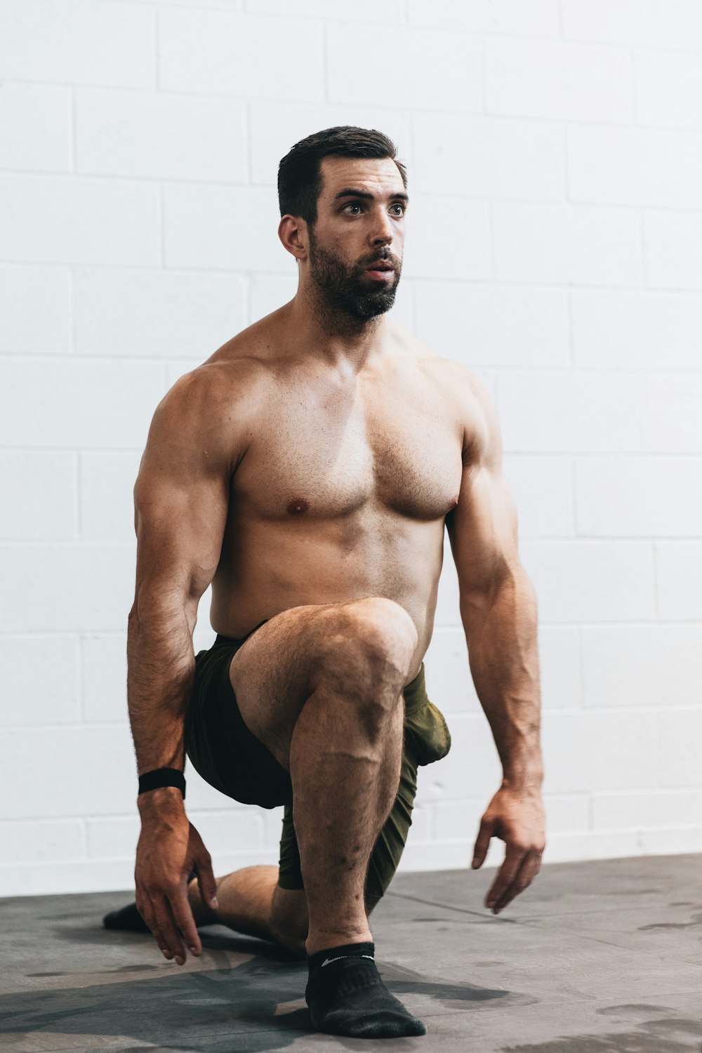 topless man in black shorts sitting on brown wooden bench