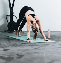 woman in black sports bra and blue denim jeans doing yoga