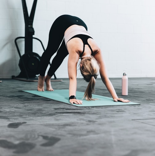 woman in black sports bra and blue denim jeans doing yoga