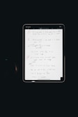 An electronic tablet displays a handwritten to-do list. The page, filled with various exercises and notes, is neatly organized with numbered bullet points and highlighted headings. The interface of the tablet is visible, with icons at the top indicating various functions such as drawing tools.