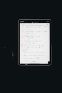 An electronic tablet displays a handwritten to-do list. The page, filled with various exercises and notes, is neatly organized with numbered bullet points and highlighted headings. The interface of the tablet is visible, with icons at the top indicating various functions such as drawing tools.