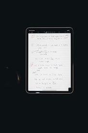 An electronic tablet displays a handwritten to-do list. The page, filled with various exercises and notes, is neatly organized with numbered bullet points and highlighted headings. The interface of the tablet is visible, with icons at the top indicating various functions such as drawing tools.