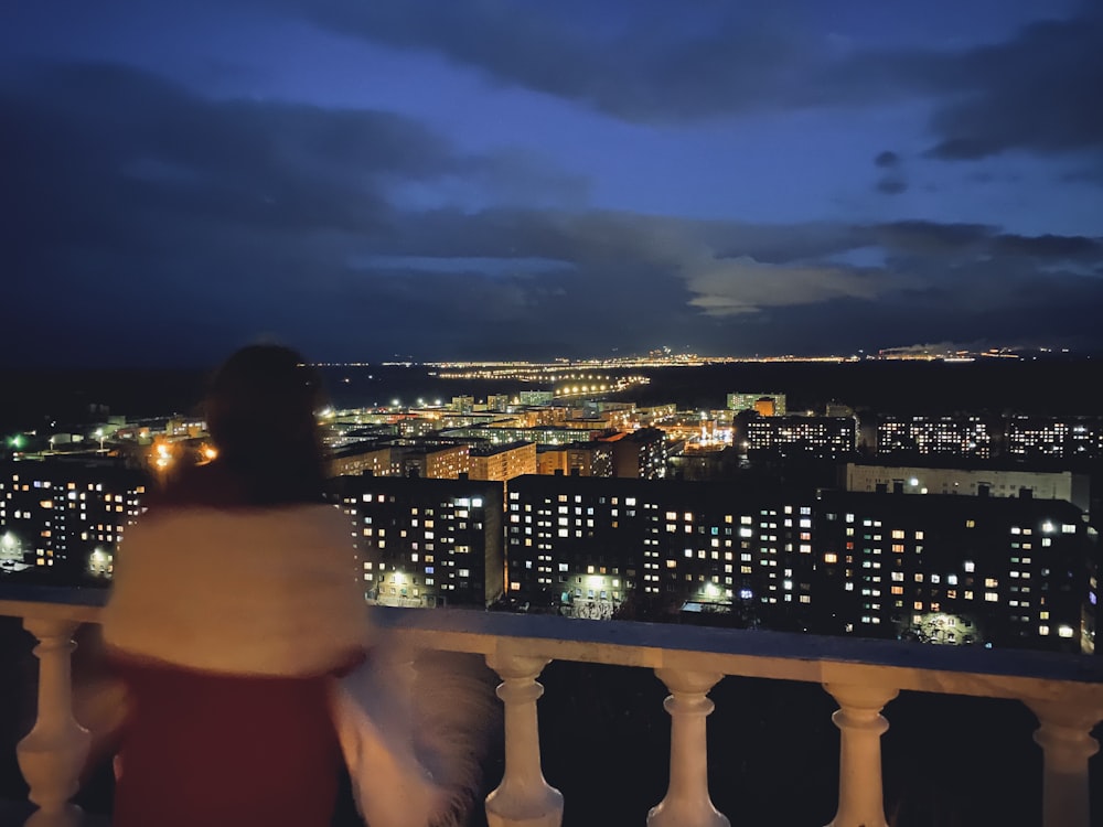 woman in white tank top standing on balcony during night time