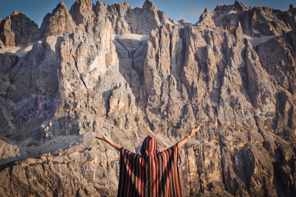 woman in red dress standing on rocky mountain during daytime