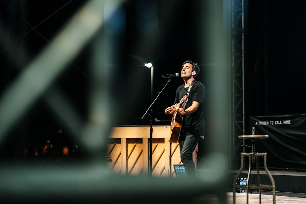 man in black t-shirt playing guitar