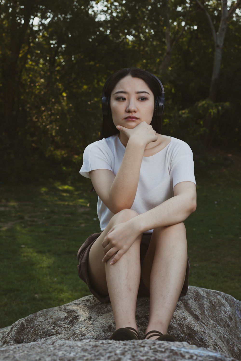 woman in white crew neck t-shirt sitting on rock