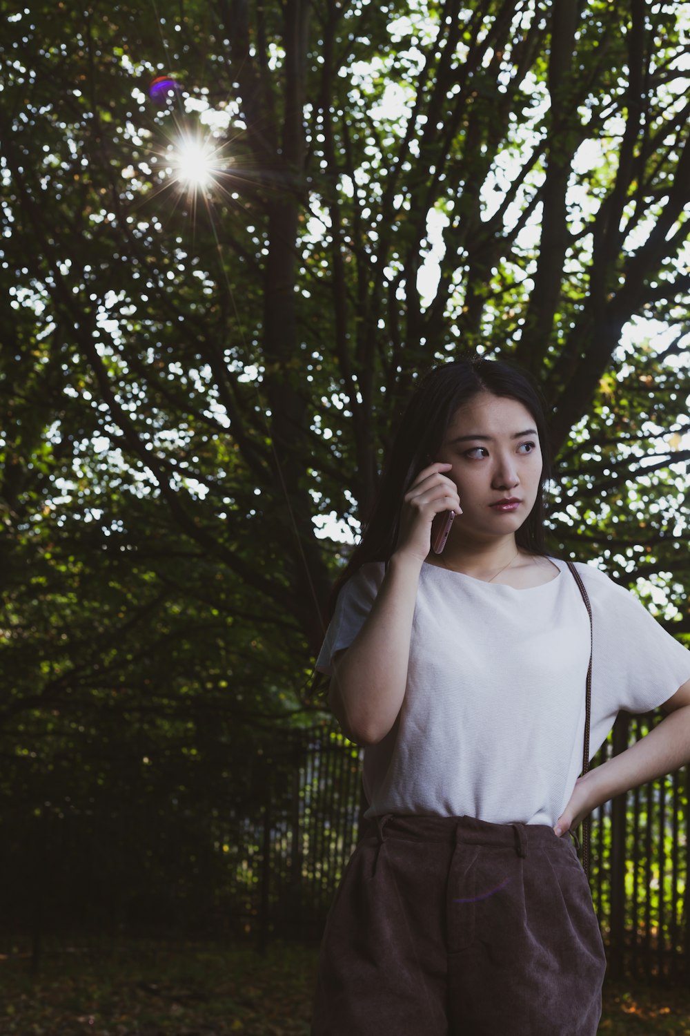 woman in white crew neck t-shirt standing under green tree during daytime