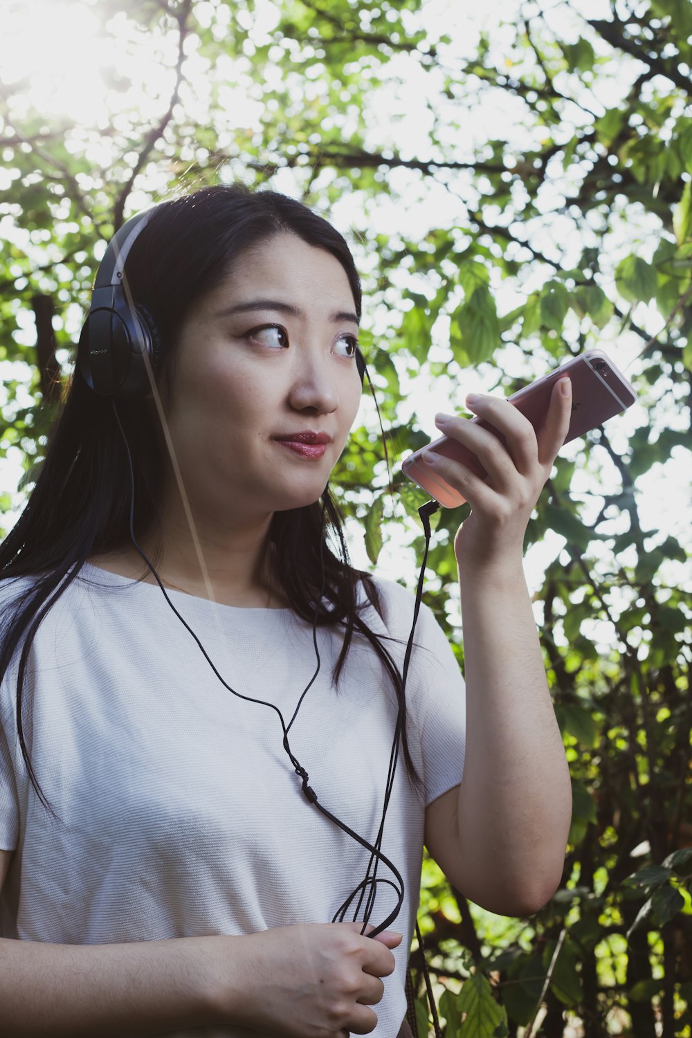 woman in white crew neck t-shirt holding brown smartphone