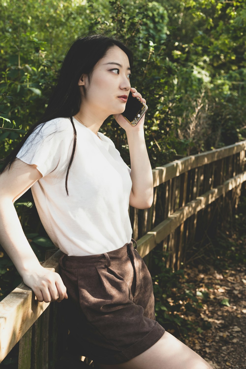 woman in white tank top and brown skirt standing near green plants during daytime