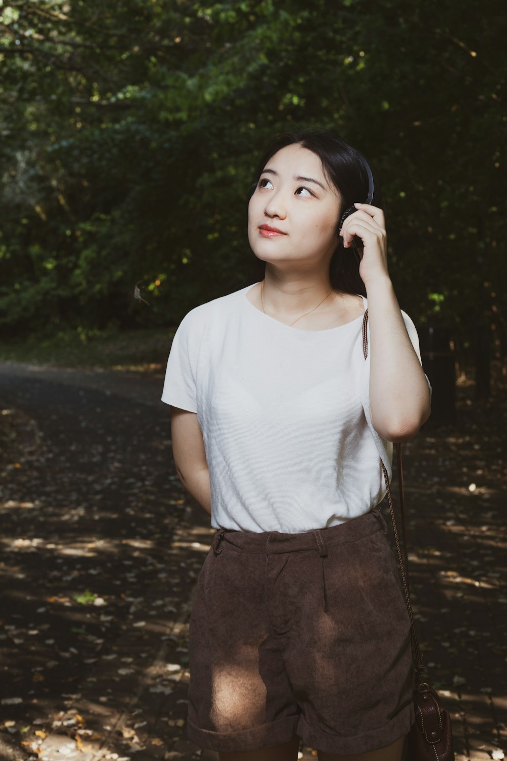 woman in white crew neck t-shirt and black skirt standing on forest during daytime