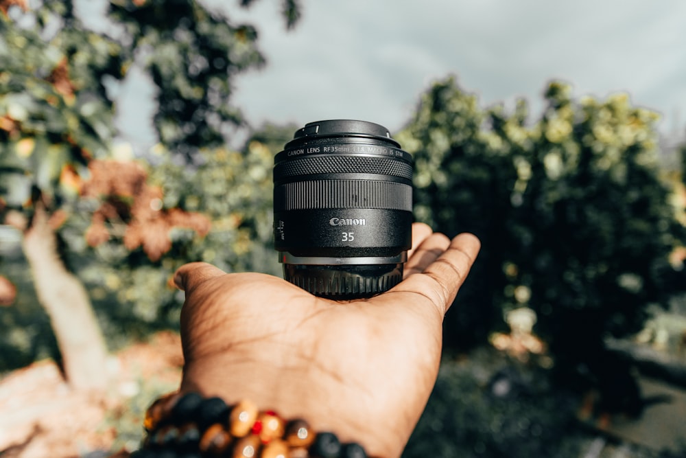 person holding black camera lens