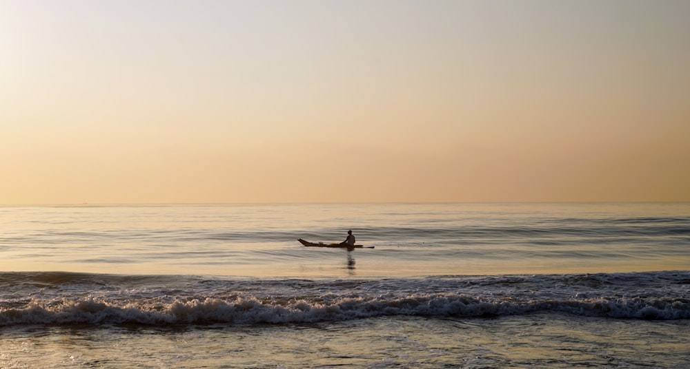 pessoa surfando nas ondas do mar durante o pôr do sol