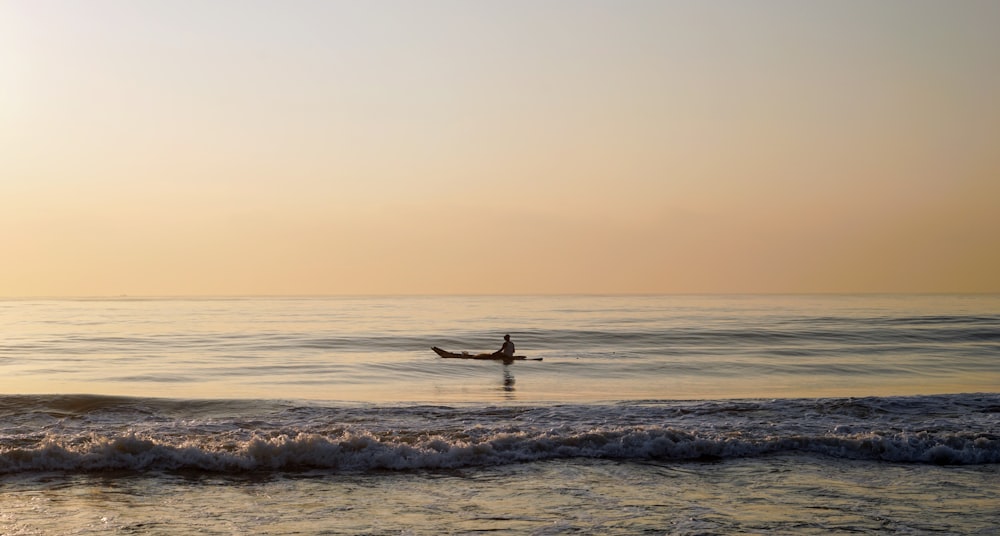 日没時に海の波でサーフィンをする人