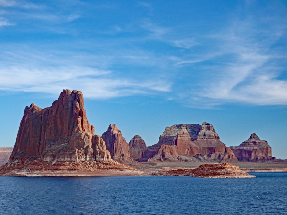 brown rocky mountain beside blue sea under blue sky during daytime