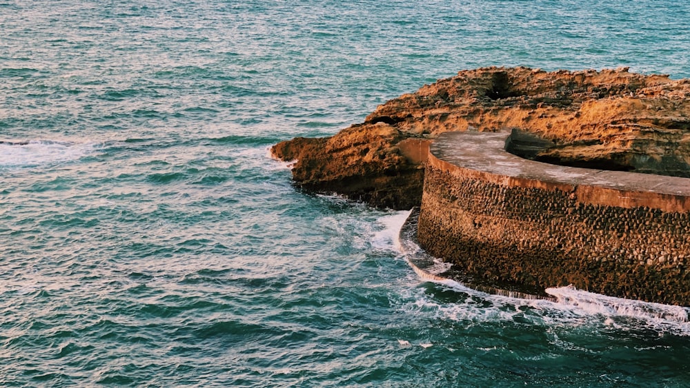 brown rock formation on body of water during daytime