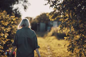 Outdoor shot of the model walking along a sunlit path, hair flowing in the breeze.