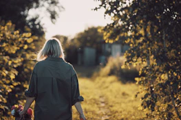 Outdoor shot of the model walking along a sunlit path, hair flowing in the breeze.