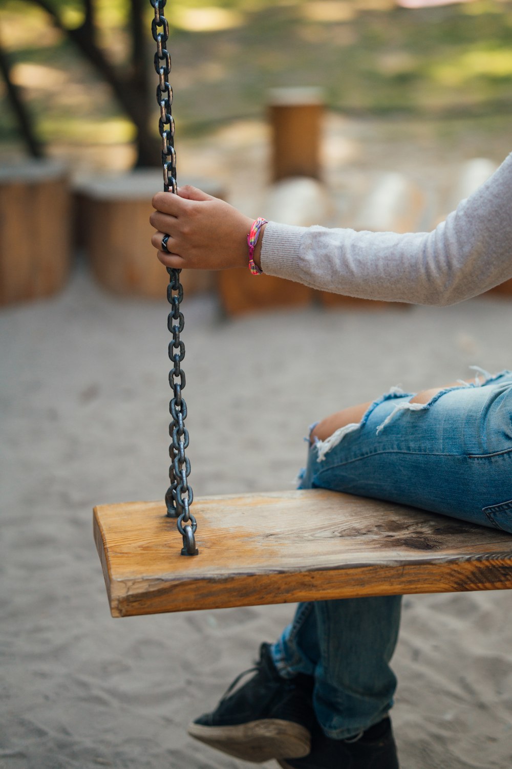 person in blue denim jeans sitting on brown wooden bench