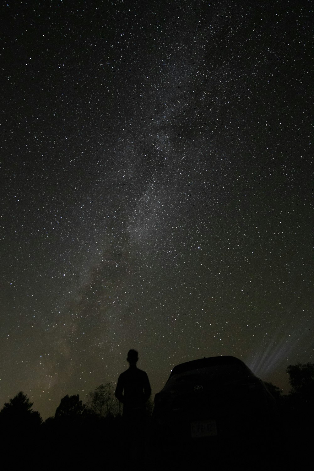 silhouette of man standing near car under starry night