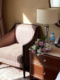 A sunlit corner with a plush armchair, soft throw blankets, and a small wooden side table adorned with a vase of fresh flowers.