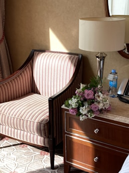 A cozy living room corner with soft lighting, a plush armchair, and a small side table adorned with a vase of fresh flowers.