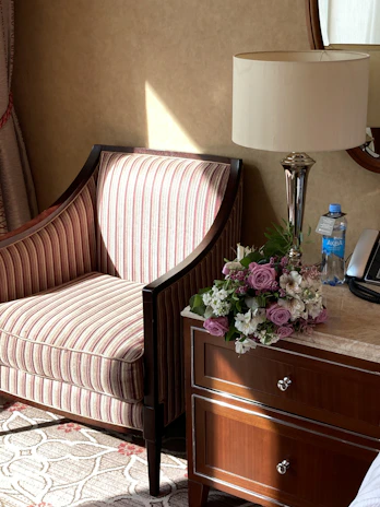 A serene corner of a cozy living room with warm sunlight, featuring elegant orchid arrangements on a wooden side table.