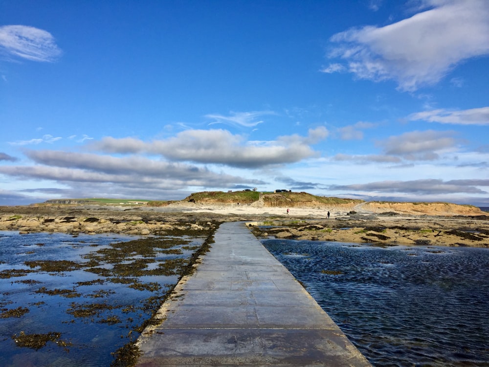 gray wooden dock on river under blue sky during daytime