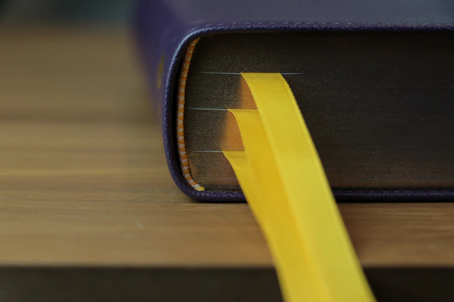 Close-up of a black and white book cover with purple and gold accents, resting on a wooden desk.