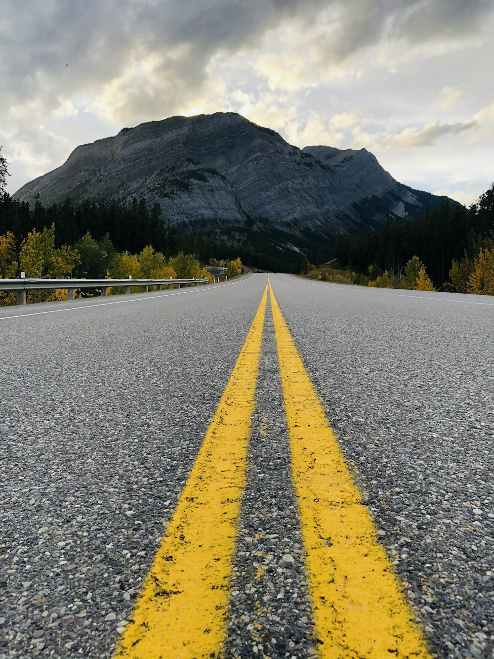 gray concrete road near green mountain during daytime
