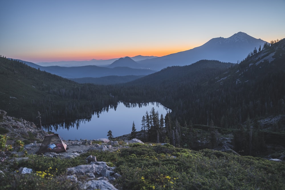 person sitting on rock near lake during daytime