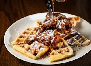 Syrup being poured over chicken and waffles with mysterious white powder on top. What is this sorcery? Part of the C9 Work WordPress Theme sample content imagery.