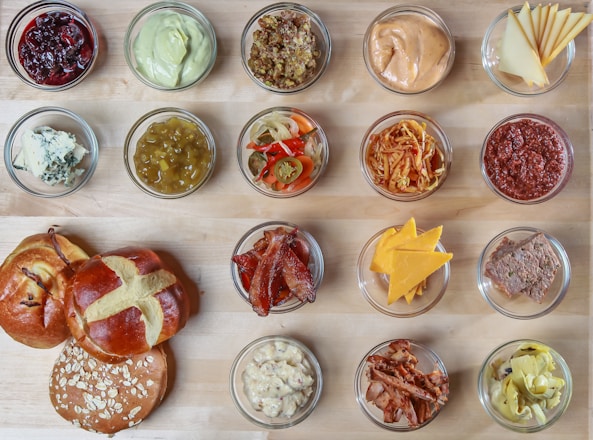 A rustic wooden table spread with assorted bagels, sandwiches, and fresh ingredients.