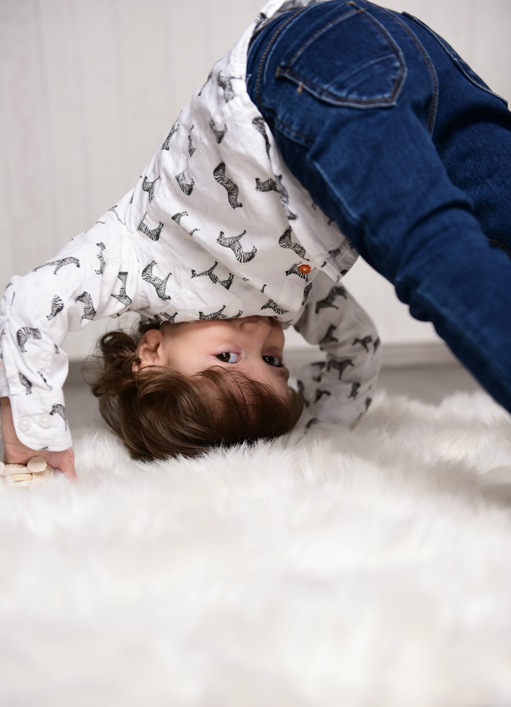 girl in white and black star printed long sleeve shirt lying on white textile