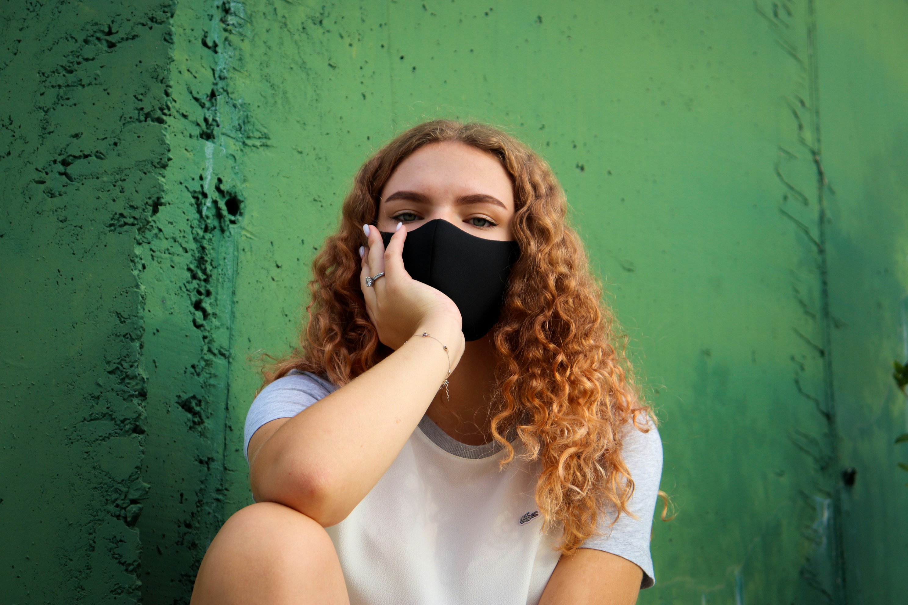 woman in white crew neck t-shirt covering her face with black mask