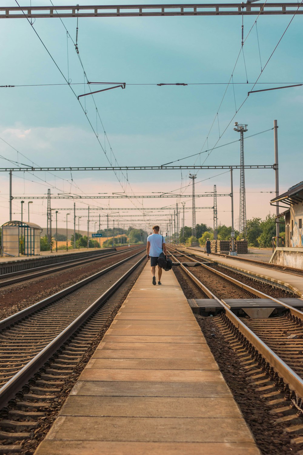 Uomo in giacca blu che cammina sul binario del treno durante il giorno