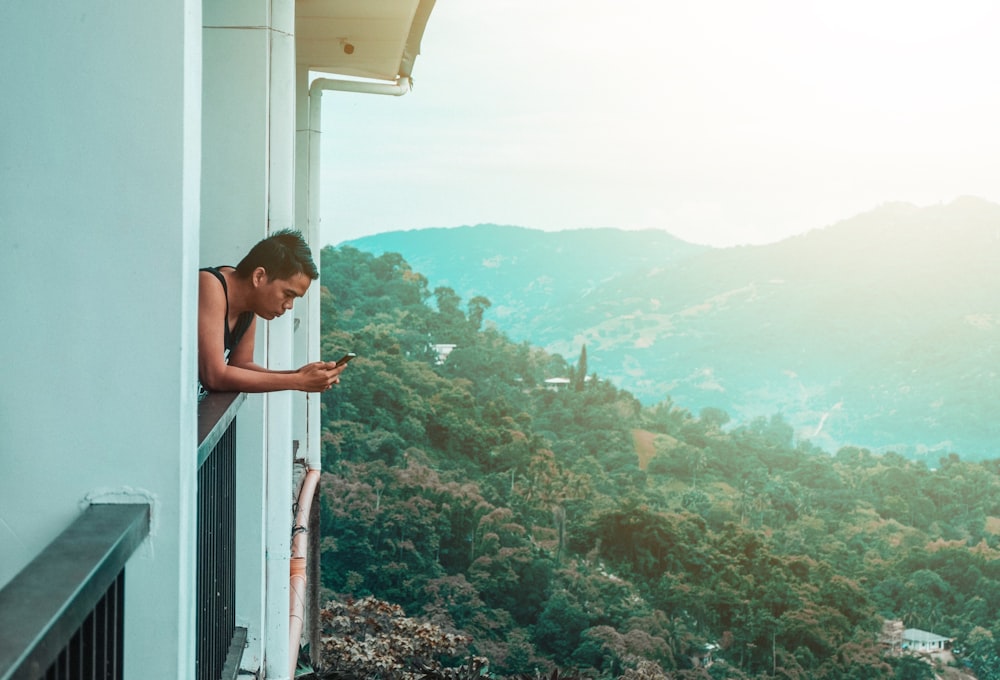 woman in black tank top sitting on white wooden fence during daytime