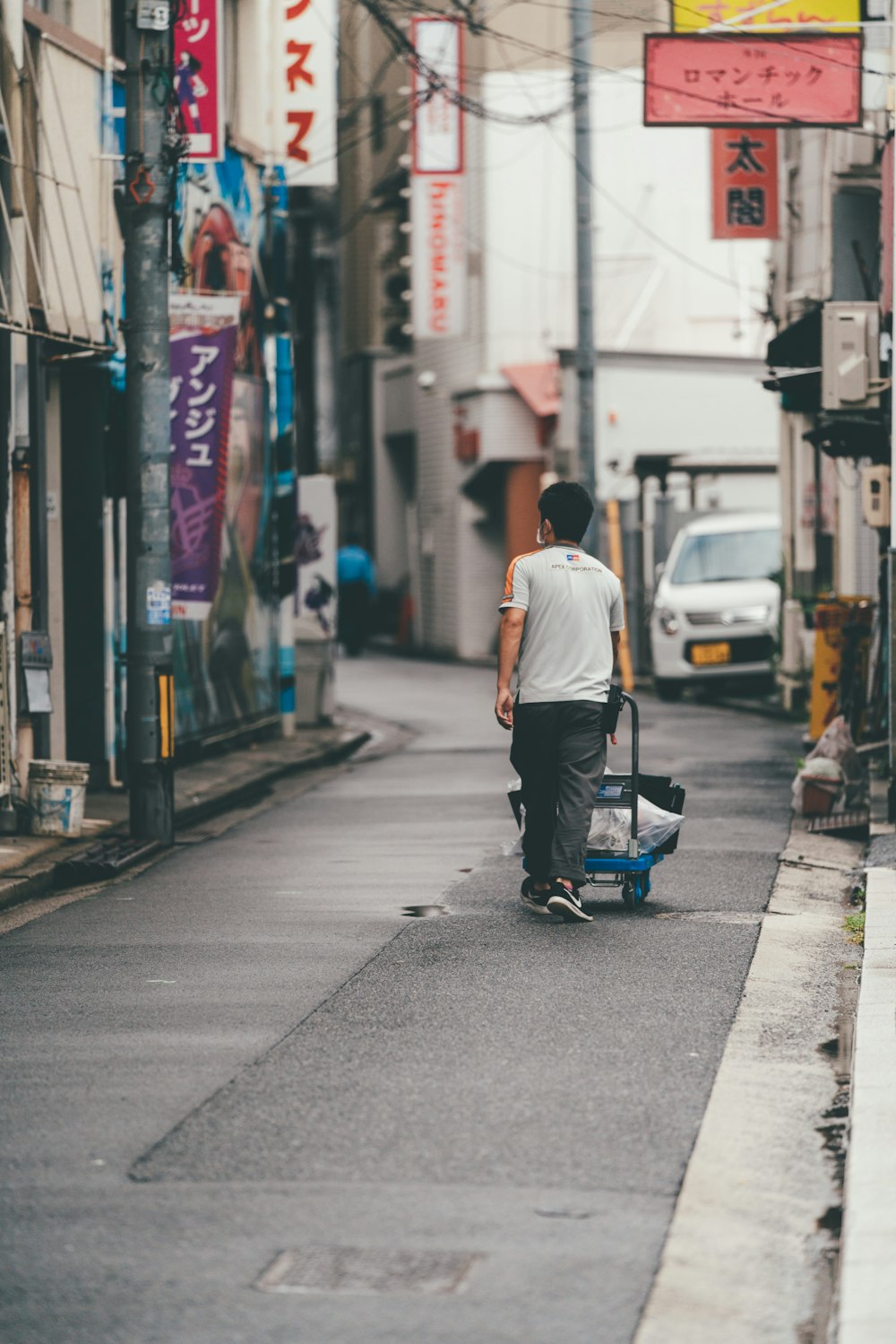 man in white t-shirt and blue denim jeans riding on blue and black kick scooter