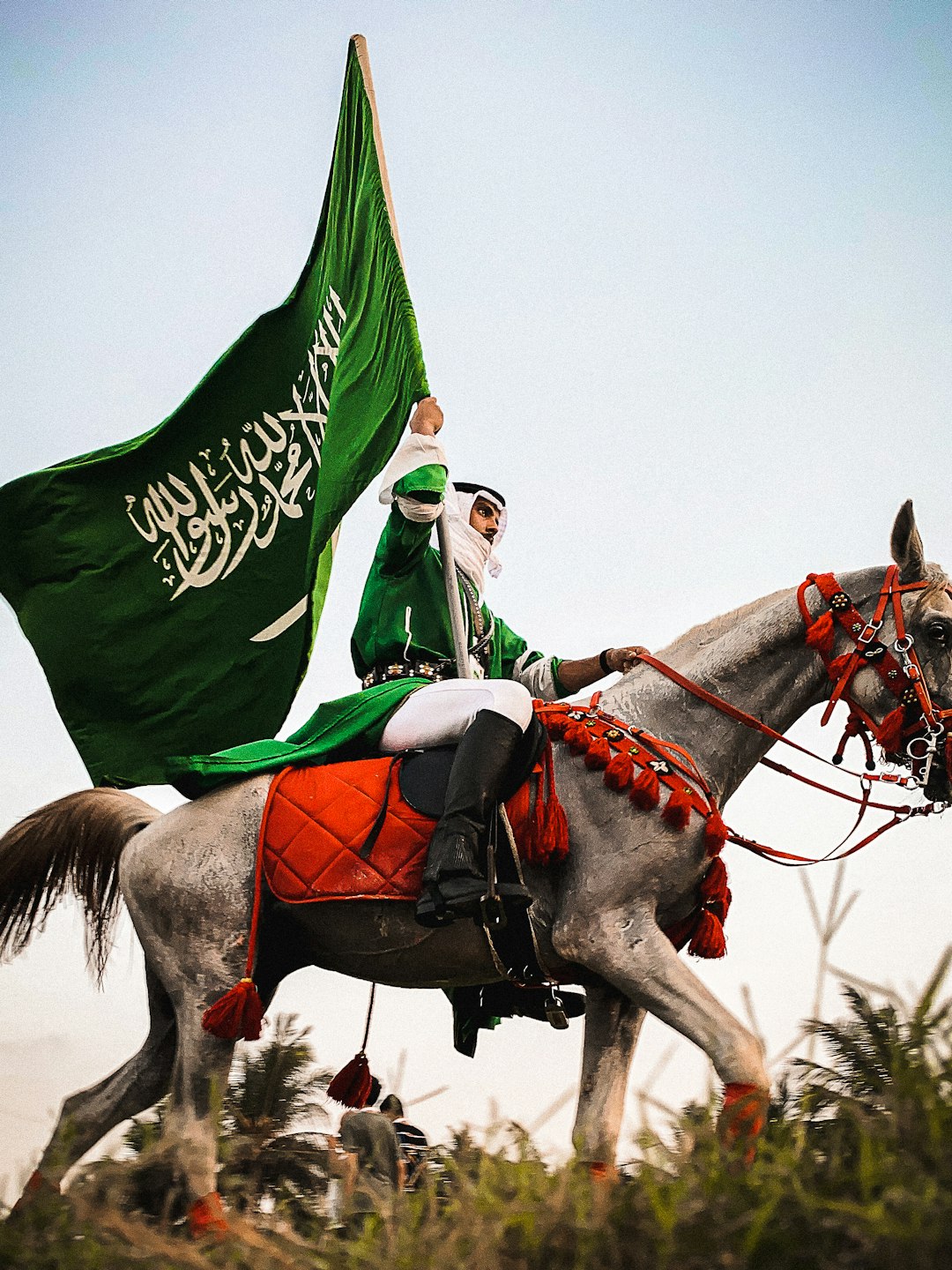 man in green and white shirt riding brown horse during daytime