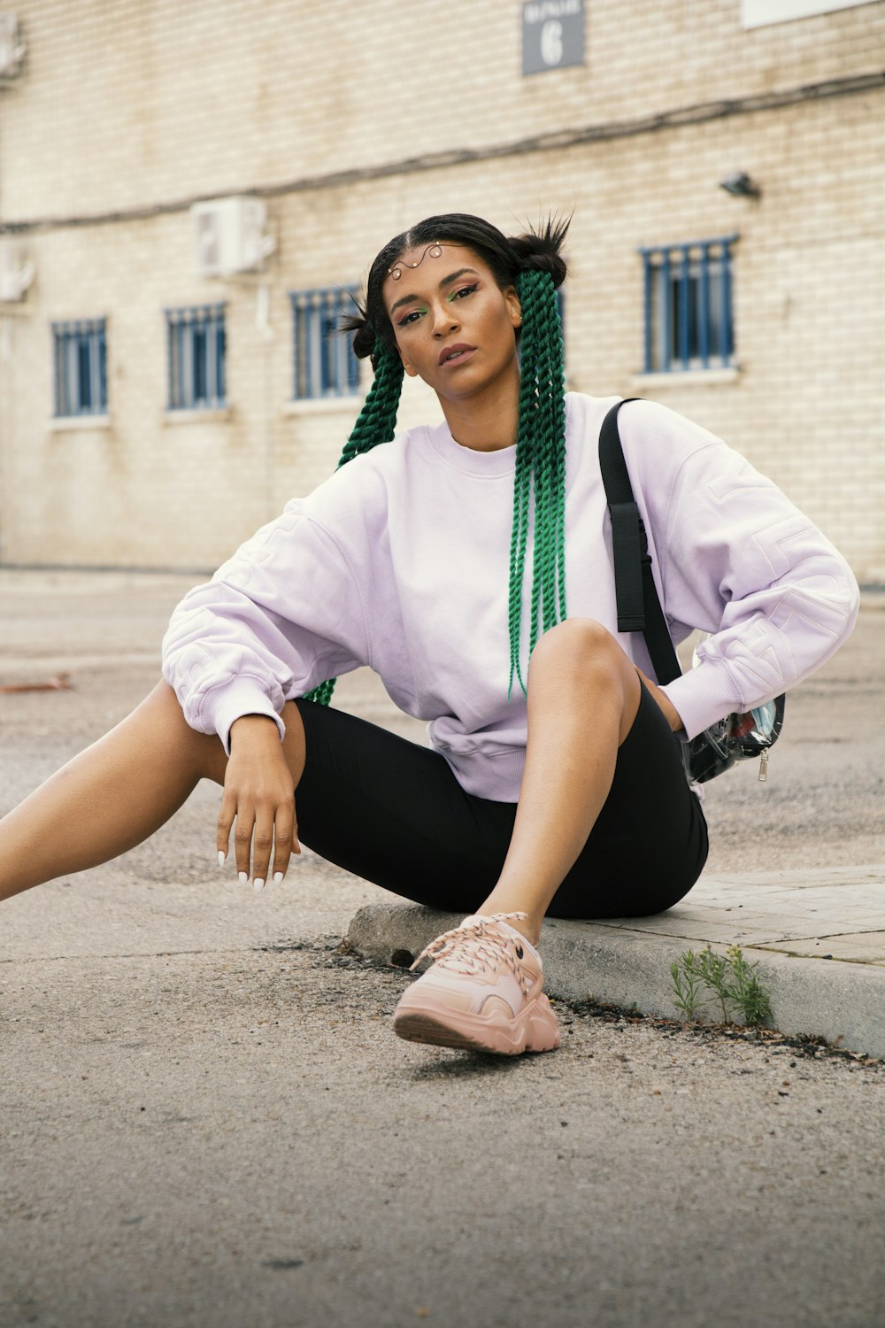 woman in pink dress shirt and black pants sitting on gray concrete pavement during daytime