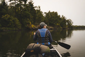 Minnesota woman in blue jacket and black backpack riding on aluminum canoe on Minnesota lake daytime