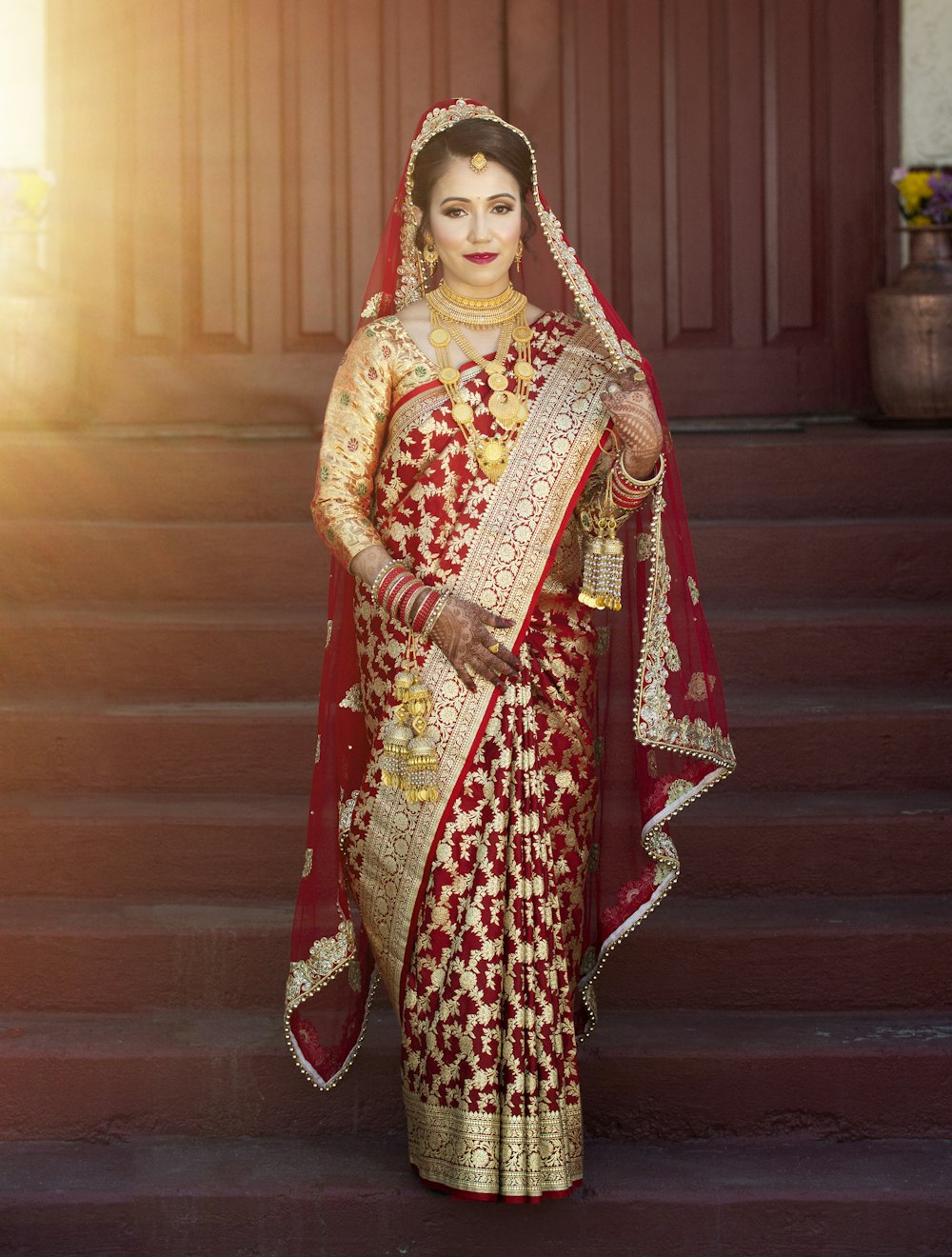 Frau in rotem und braunem Sari auf braunem Holzboden