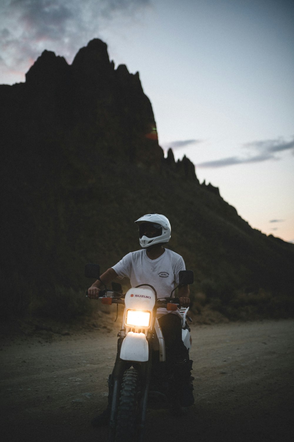man in white helmet riding motorcycle on gray sand during daytime