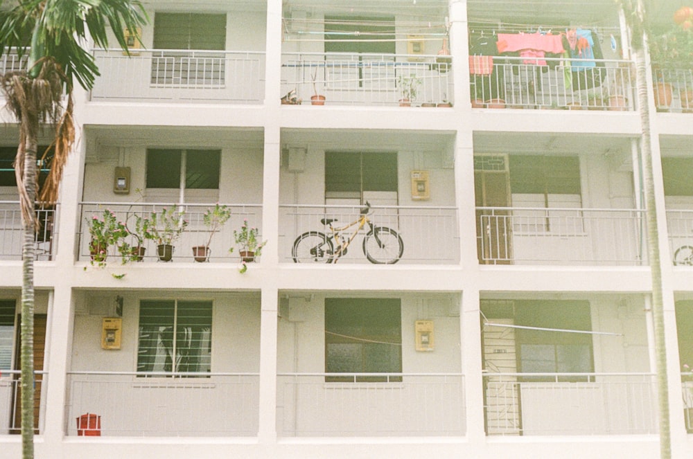 white and black bicycle hanging on white concrete building