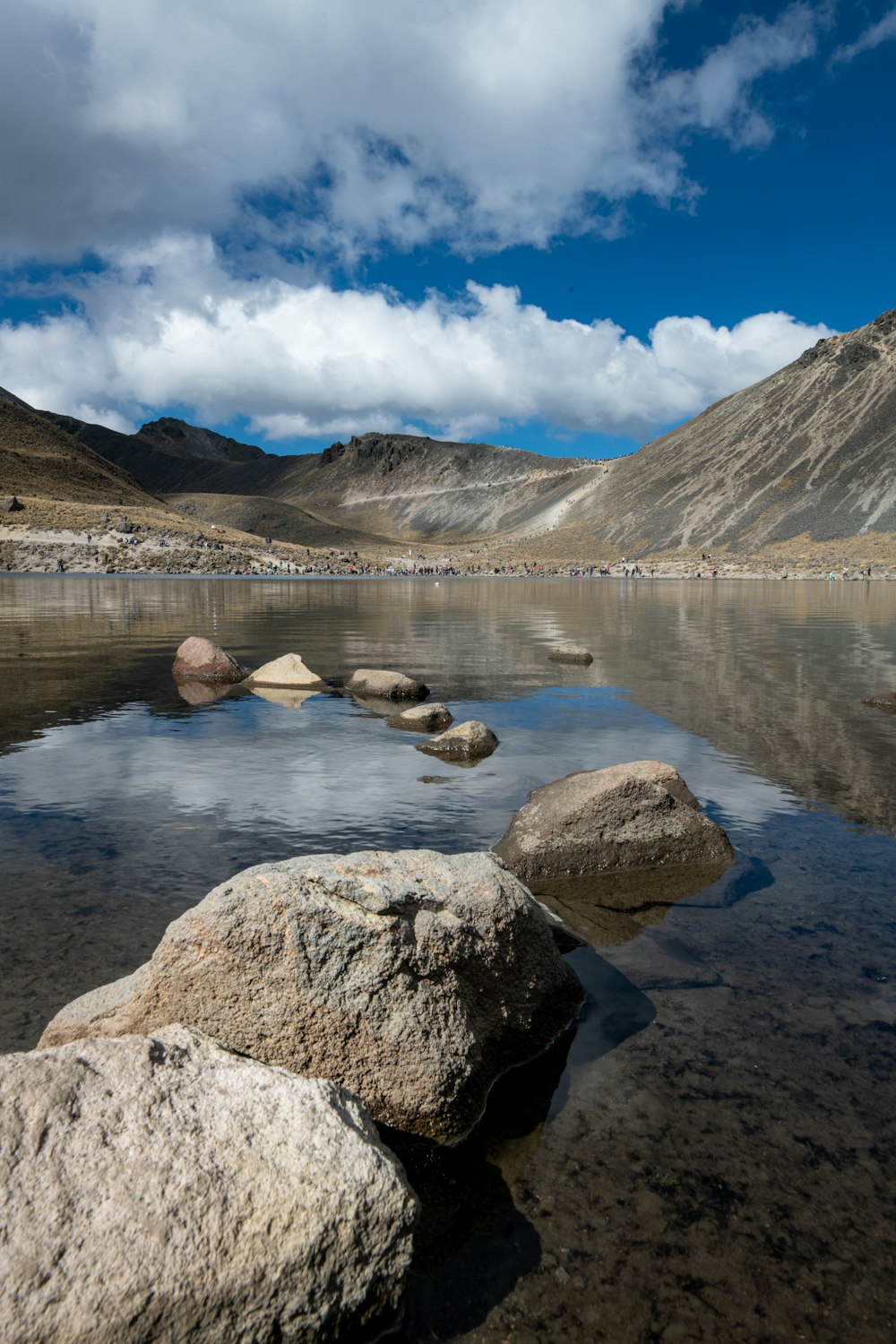 brown and white mountains near lake under blue sky during daytime