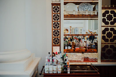 Elegant brass-accented bar cart showcasing an array of premium imported spirits against a deep navy backdrop.
