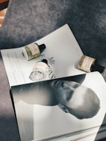 An elegant flat lay of men's accessories and a signature fragrance bottle on a polished black surface.