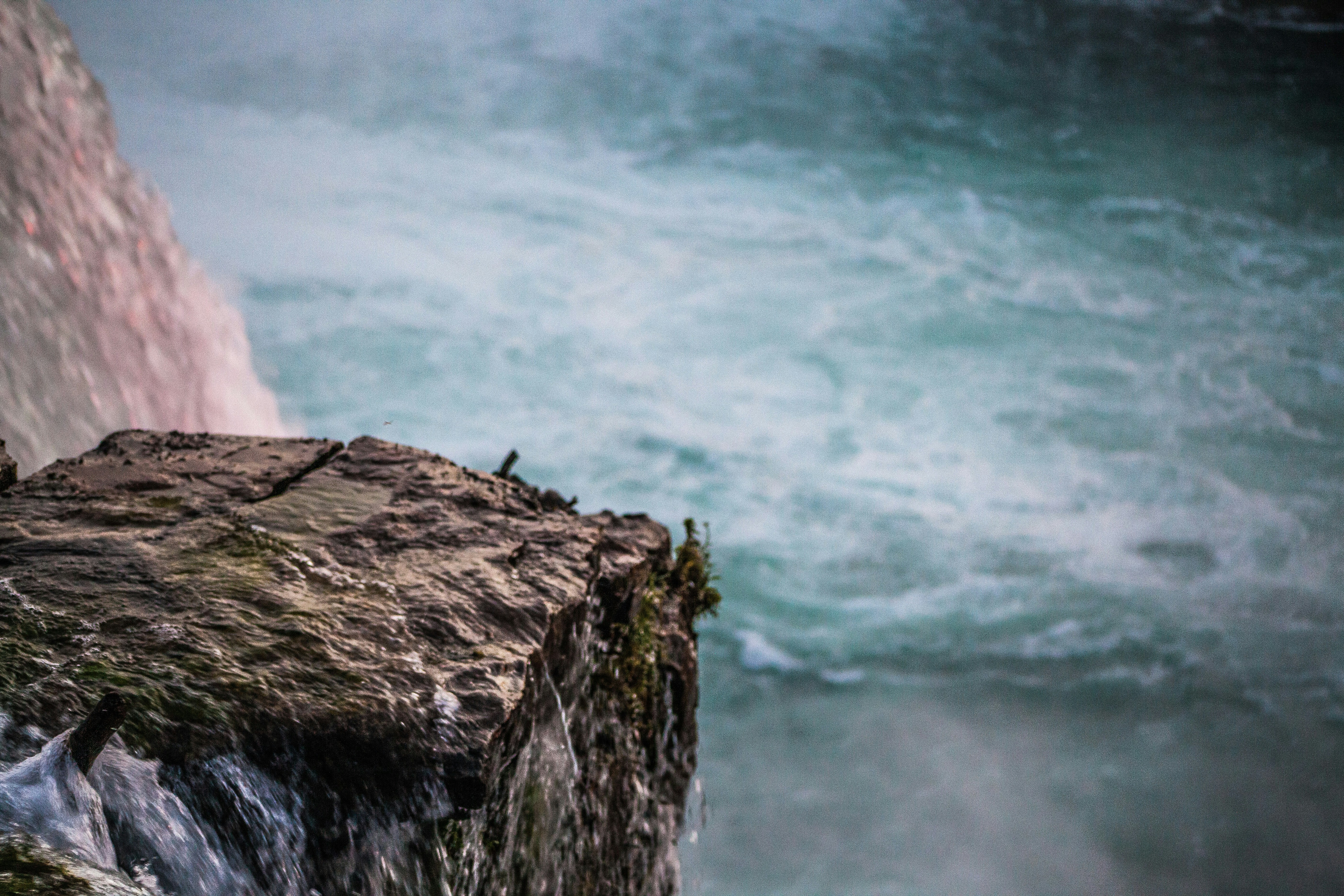 person standing on brown rock near body of water during daytime