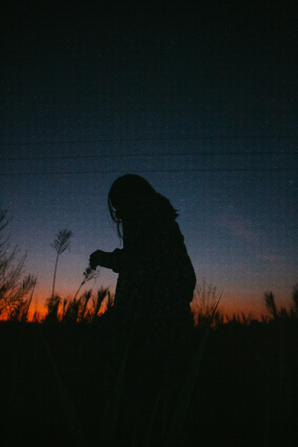 silhouette of woman standing on grass field during night time
