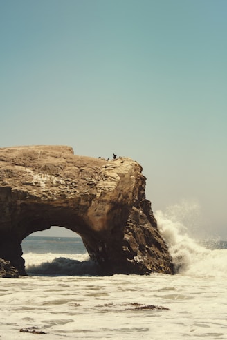 person standing on rock formation in sea during daytime