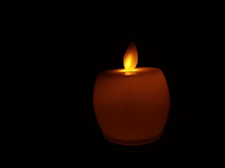 Close-up of a flickering candle flame casting gentle shadows on a black surface.
